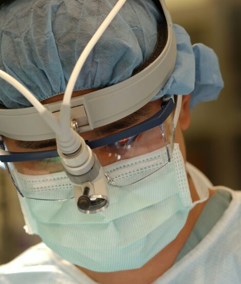 Healthcare provider in mask and head-mounted microscope
